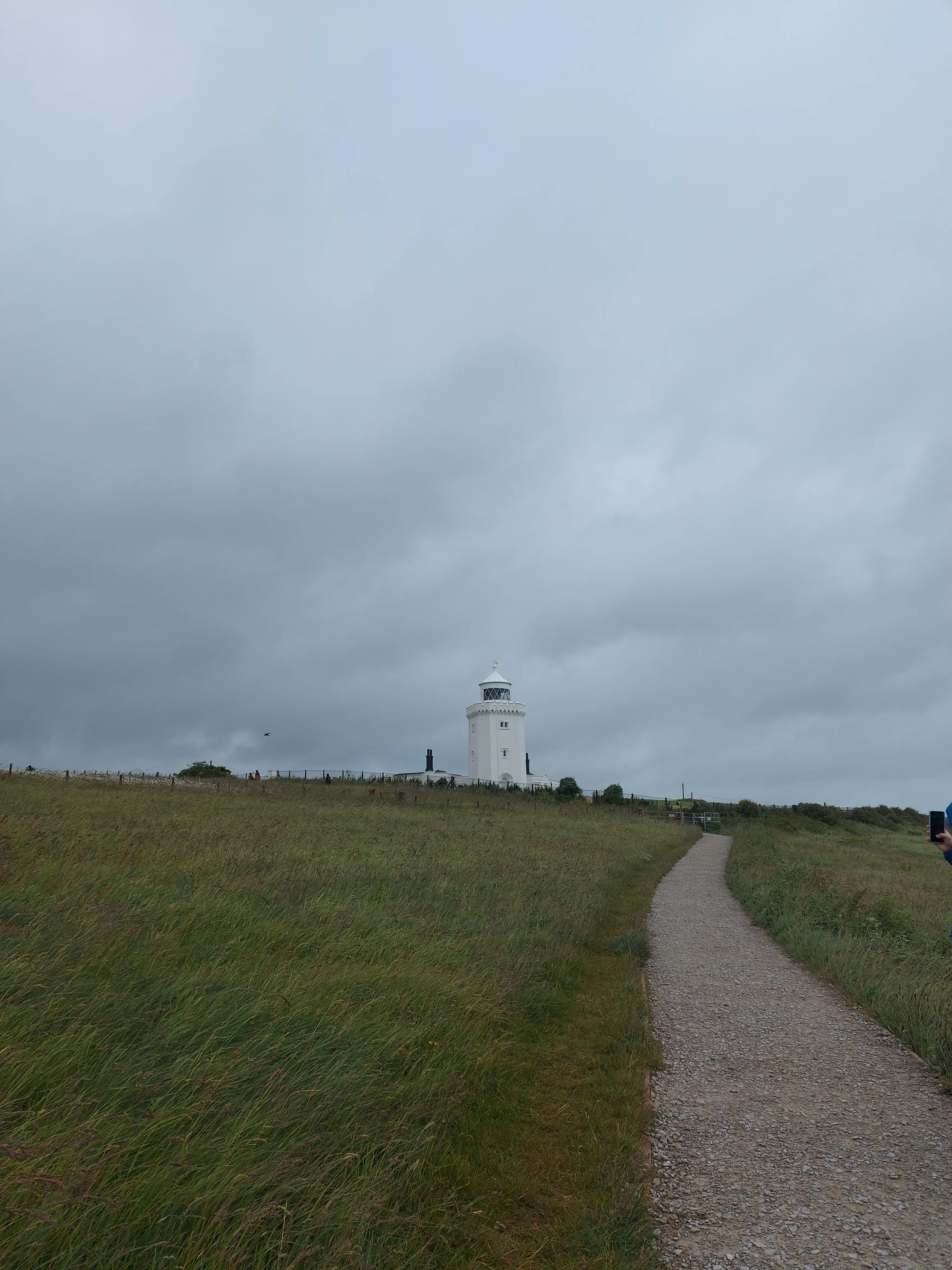 South Foreland Lighthouse on the background of green grass fields with grey skies.