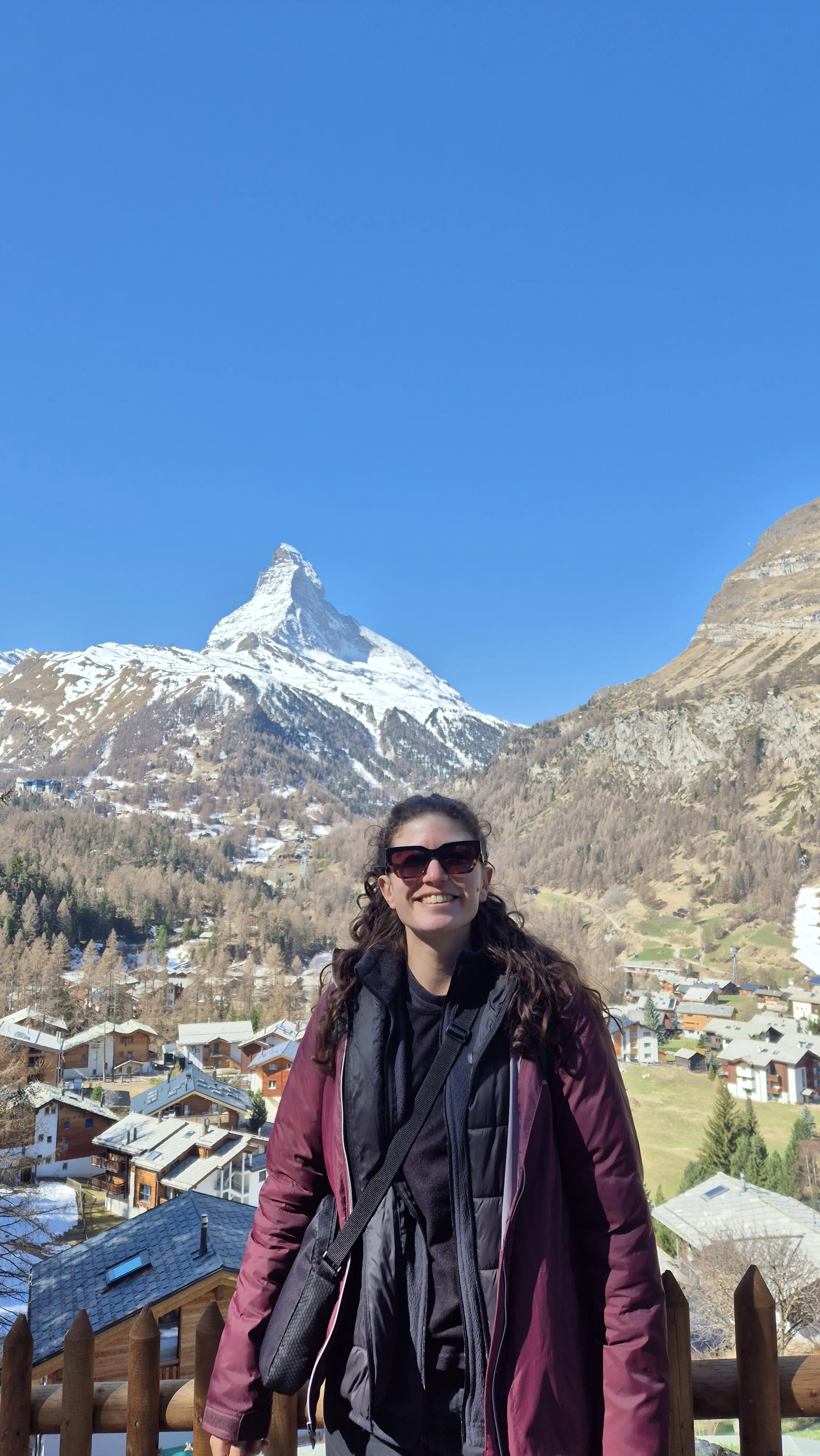 Profile picture of a woman with sunglasses standing in front of the Matterhorn.